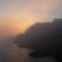Sunset glowing through fog behind the Battery.