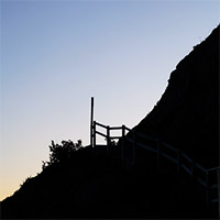 A signpost and steep hillside silhouetted against the sky.